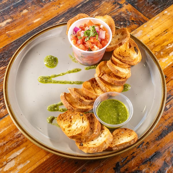 Bruschetta with fresh tomato salsa and vibrant green pesto on a plate.