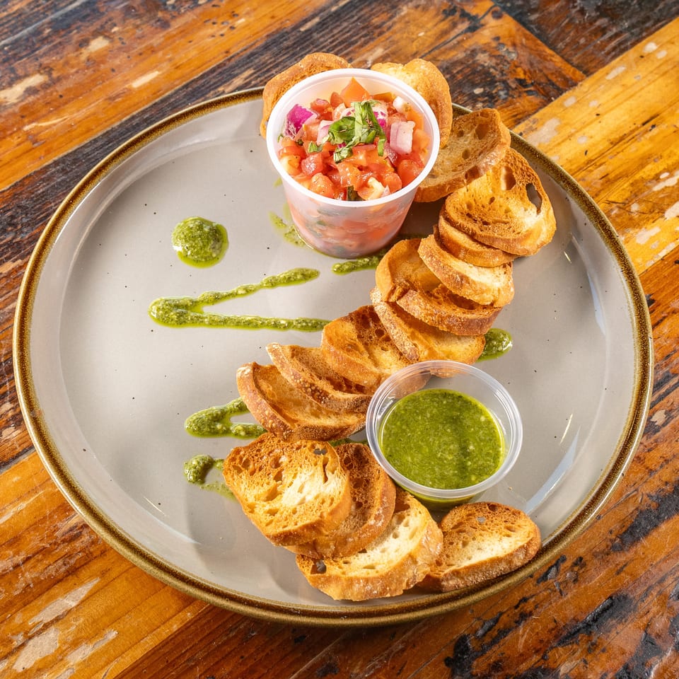 Bruschetta with fresh tomato salsa and vibrant green pesto on a plate.