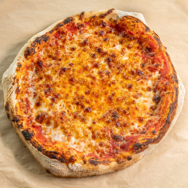 Round cheese pizza with bubbly melted cheese and a charred crust on brown paper.