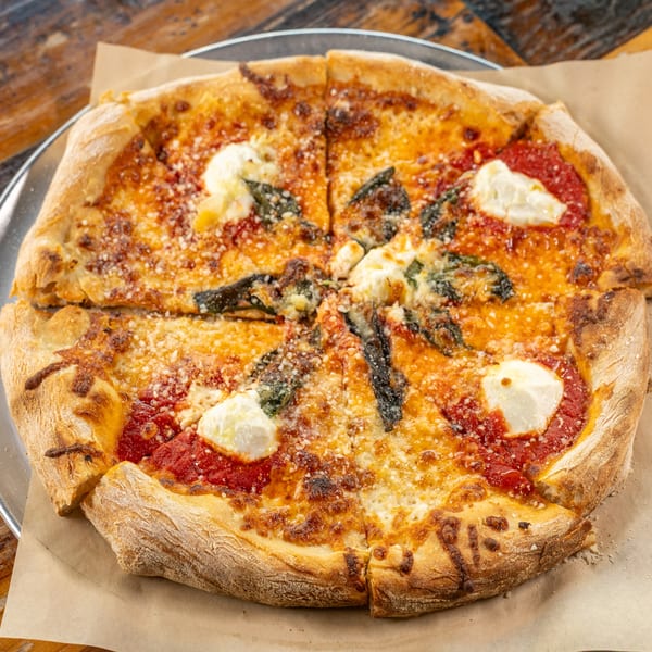 Sliced Margherita pizza with tomato sauce, mozzarella, basil, and dollops of ricotta on a metal tray.